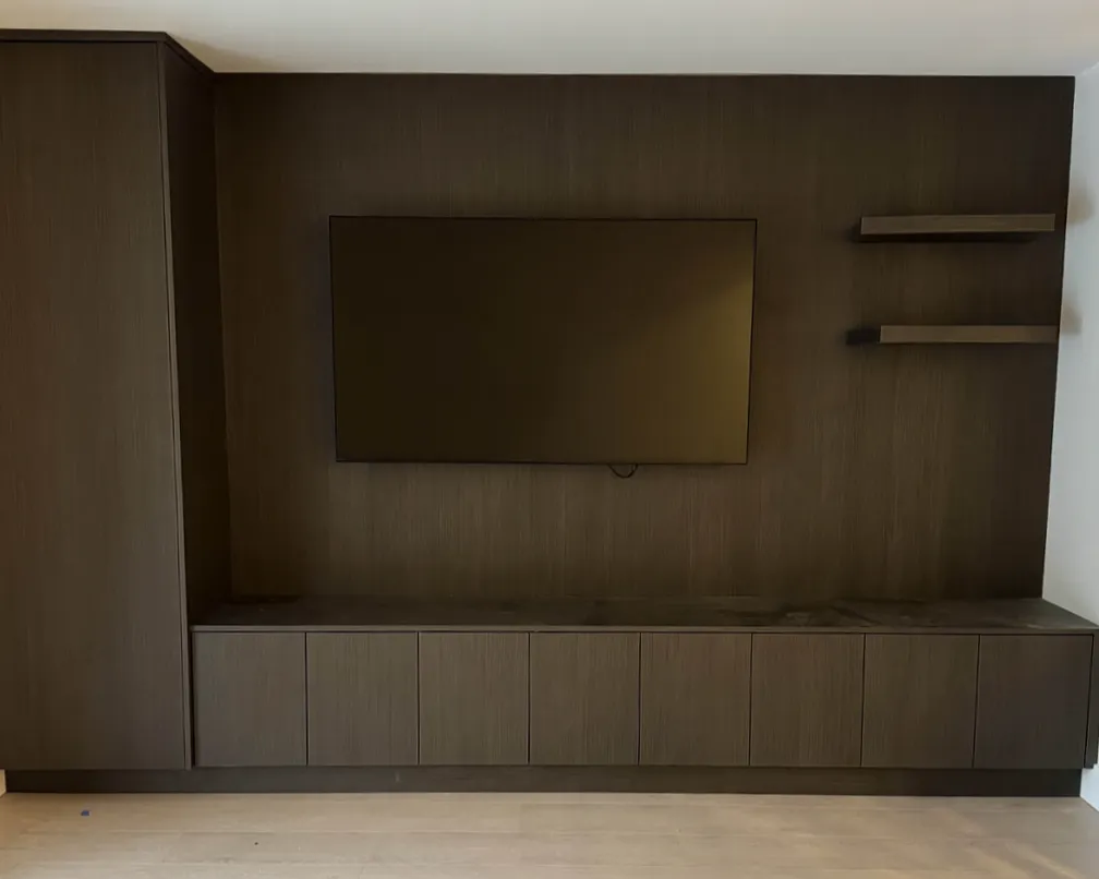 Dark Wood Media Wall — A seamless media wall with open shelving wrapped in rich, dark wood for a bold yet restrained presence.
